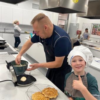 Vater und Sohn backen Waffeln in einer großen Küche.