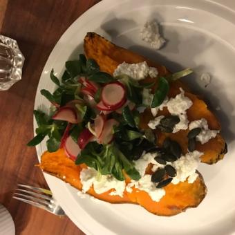 Eine gebackene Süßkartoffel, aufgeschnitten und gefüllt mit Ziegenfrischkäse, dazu Radieschen-Feldsalat.