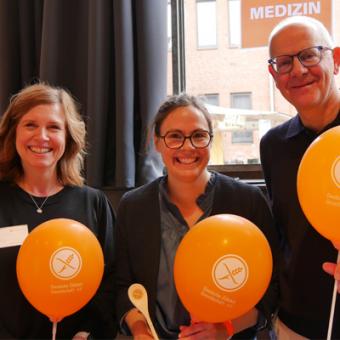 Dr. Tina Schomacher, Nicole Burgstett und Dr. Söhnke Dammann stehen nebeneinander und haben Luftballons in der Hand und strahlen