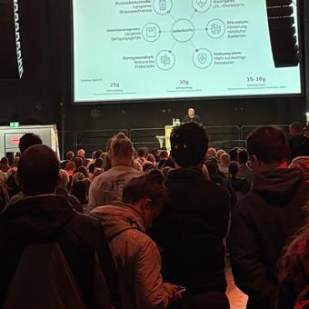 Ein Diagramm ist auf einer Leinwand davor sitzt Dr. Söhnke Damann und referiert über Zöliakie