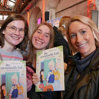3 Aufsichtsräte  haben das Kinderbuch der unsichtbare Gast in der Hand und lächeln