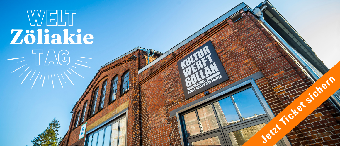 Aussenansicht der Kulturwerft Golan- ein altes Fabrikgebäude mit blauem Himmel - links oben ist das Logo der durchgestrichenen Ähre
