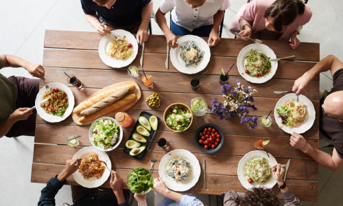 Gruppe Menschen sitzt an einem gedeckten Tisch beim gemeinsamen Essen