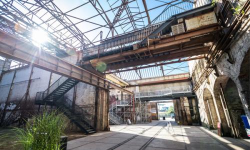 Innenansicht der Golanwerft. Ein Dach mit Glas und vielen Stahlträgern, ein lichtdurchfluteter Gang - ein altes wunderschönes Fabrikflair